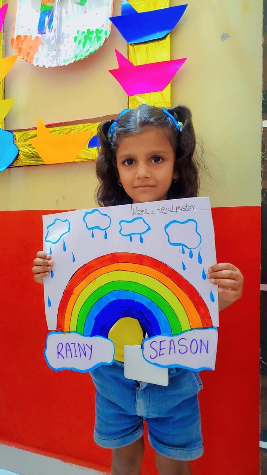 A child showing artwork made at Sunflower Preschool